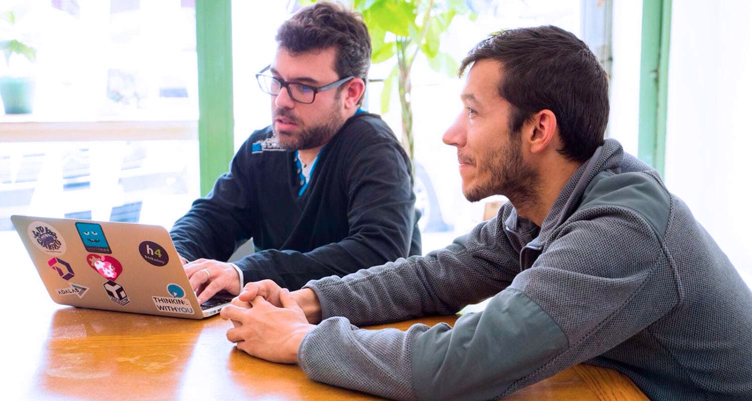 Dos autónomos de la empresa Thinking With You están trabajando en Freeland Coworking, reunidos en una mesa.